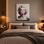 Πίνακας Marilyn Monroe Pop Art με έντονη ροζ τσιχλόφουσκα, πάνω από κρεβάτι σε μοντέρνο υπνοδωμάτιο με ζεστό φωτισμό.